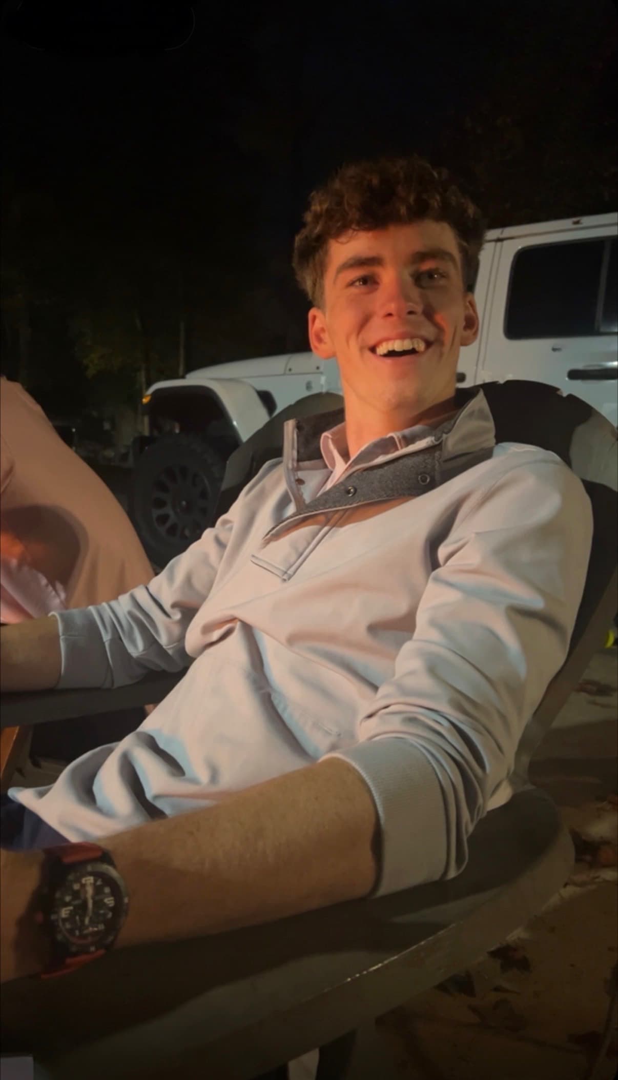 Jimmy Gracey smiling, seated outdoors in the evening